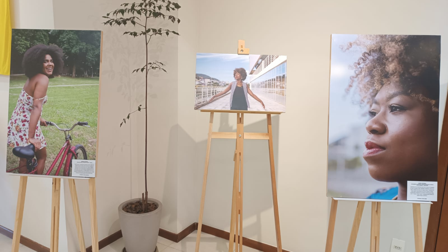 Três quadros em cavaletes, com fotos ampliadas de mulheres pretas