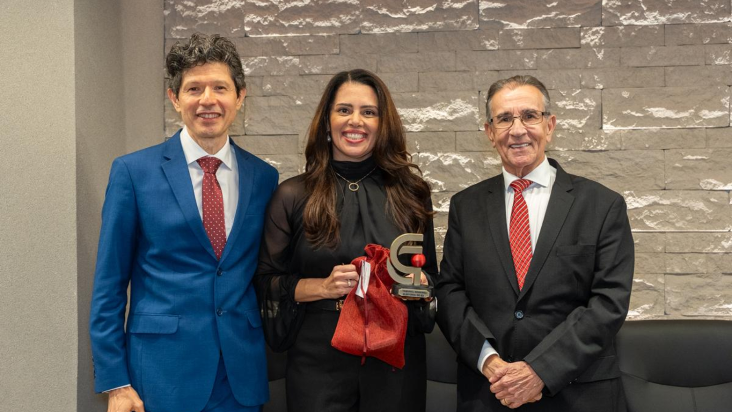 a juíza federal com o troféu nas mãos, ladeada pelo juiz Alceu Mauricio e pelo presidente do TRE-ES