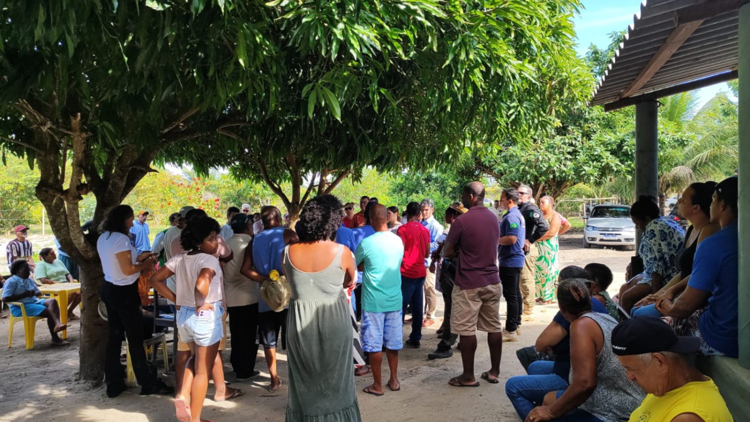 Famílias participando da reunião, sob a sombra de uma árvore