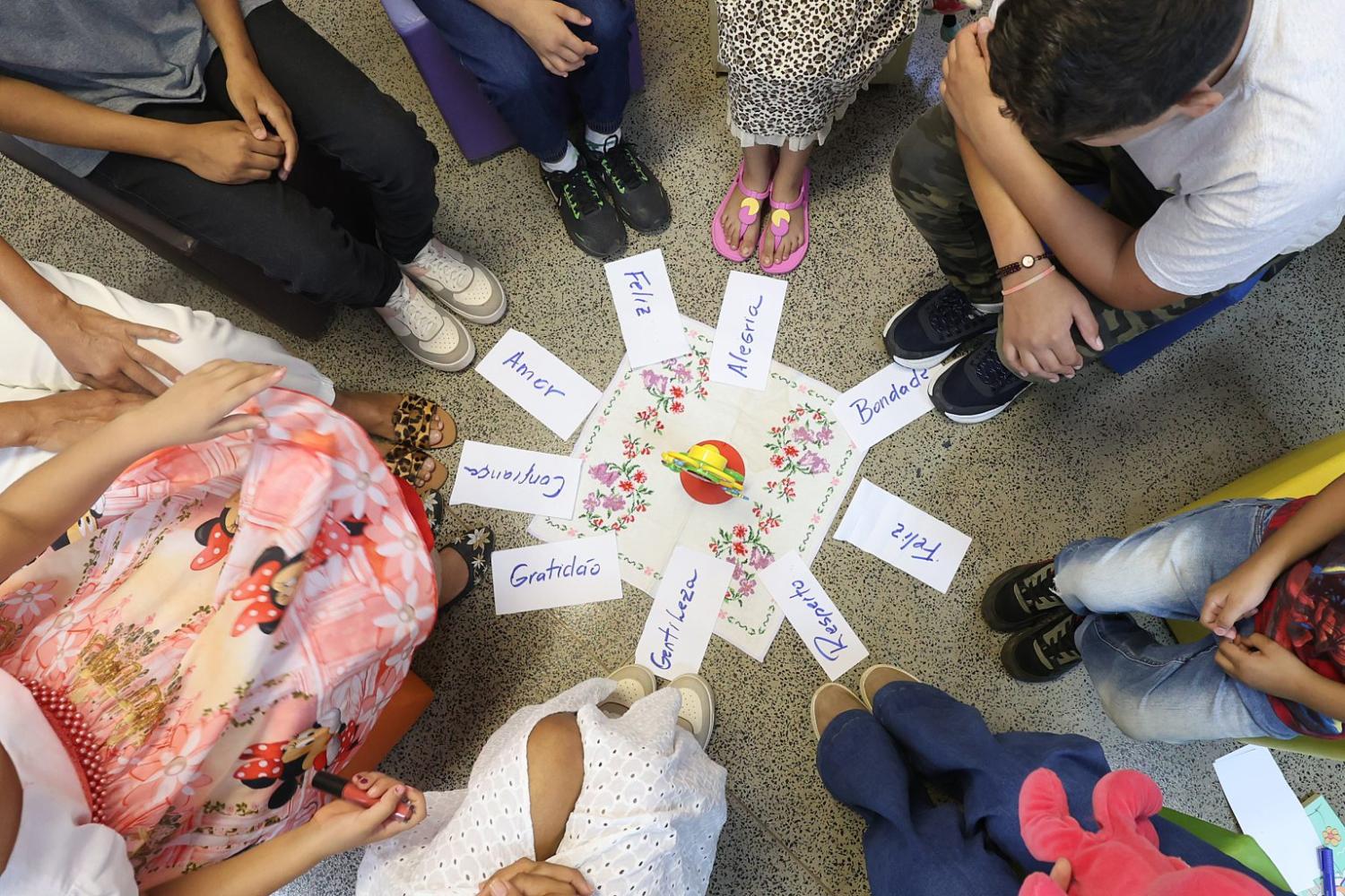 Pessoas sentadas em volta de um papel no chão com várias mensagens