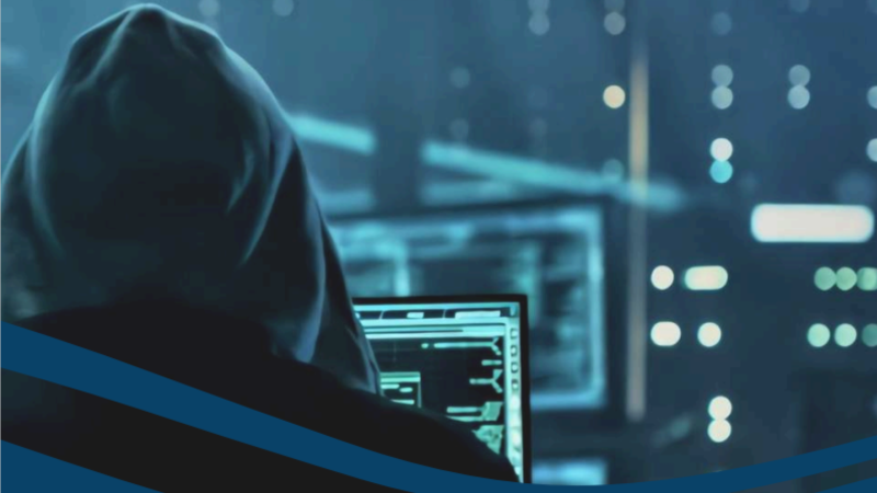 racker de costas, com capuz preto, ao computador