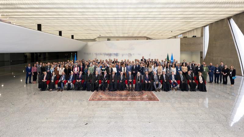 Grupo de mulheres e homens de raças diferentes no meio de um grande salão com teto e paredes brancas