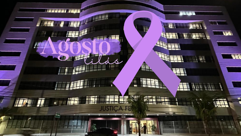 Fachada da sede da Justiça Federal, em Vitória, iluminada de lilás. Por cima da foto, um laço lilás e o texto "Agosto Lilás"