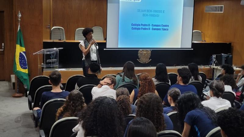 mulher preta palestrando para estudantes em auditório