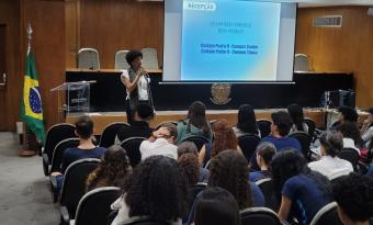 mulher preta palestrando para estudantes em auditório