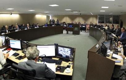 plenário em forma de mesa redonda com várias pessoas sentadas 