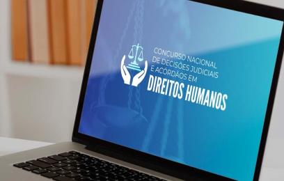 Imagem de um laptop. Na tela, o banner do Concurso Nacional de Decisões Judiciais e Acórdãos em Direitos Humanos