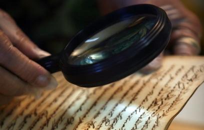 Imagem de pessoa lendo documento escrito à mão com lupa