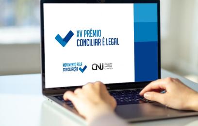 Pessoa digitando num laptop. Na tela, o banner do prêmio Conciliar é Legal