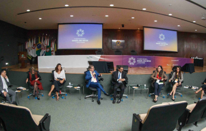 5 mulheres e 3 homens, sentados, participando de roda de conversa, num auditório